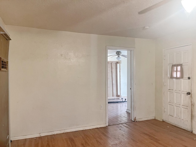 spare room with light wood-style flooring, baseboards, and a textured ceiling