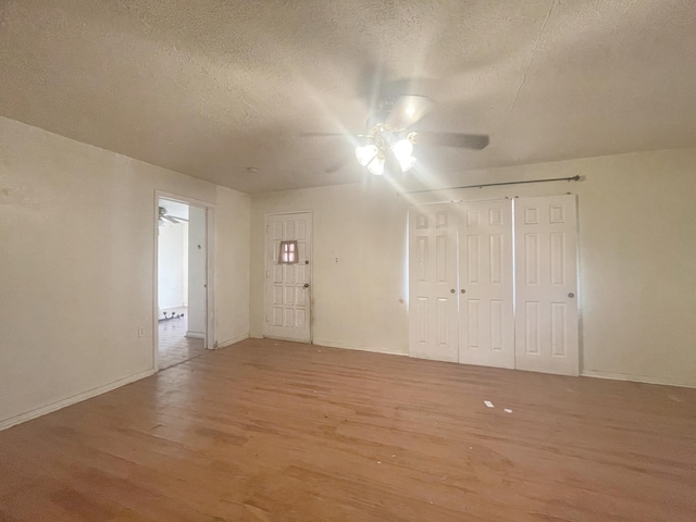 interior space with light wood-type flooring, ceiling fan, and a textured ceiling