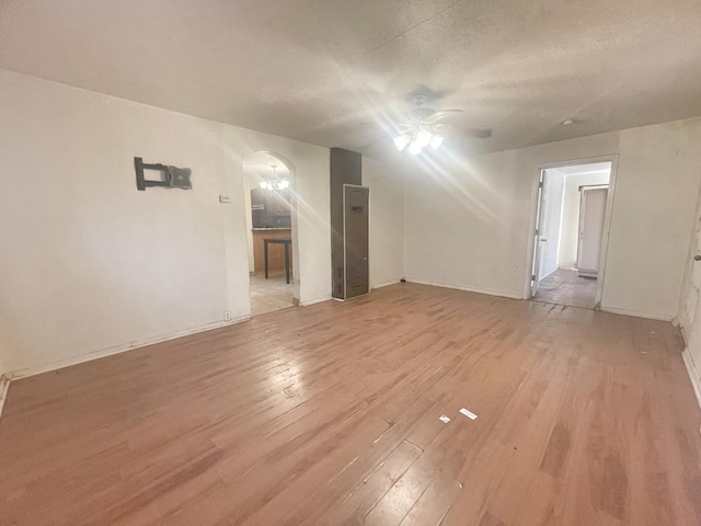 interior space featuring baseboards, ceiling fan, light wood-style flooring, and a textured ceiling