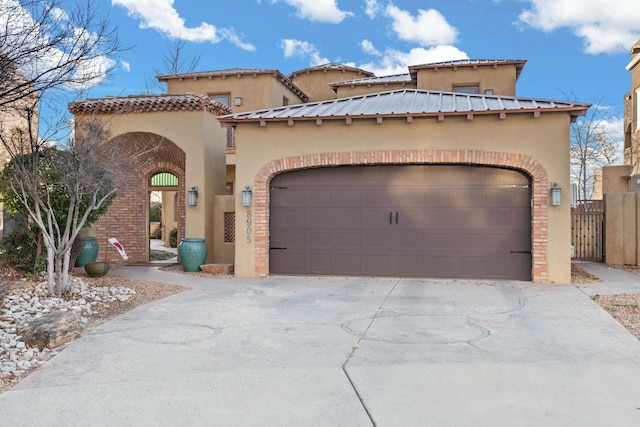 mediterranean / spanish-style home with brick siding, stucco siding, concrete driveway, fence, and a garage