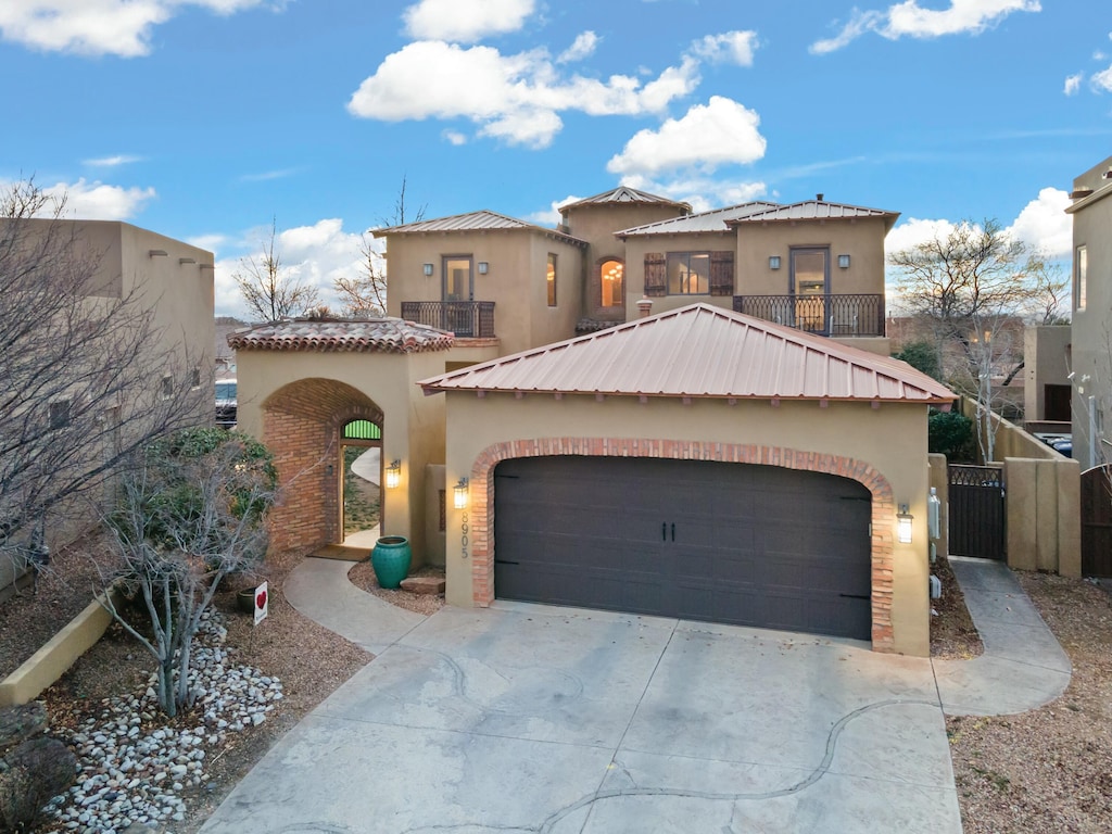 8905 N Oakland Ct NE, Albuquerque, NM 87122 - mediterranean / spanish home with concrete driveway, a balcony, an attached garage, and stucco siding