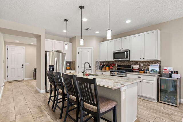 kitchen with wine cooler, stainless steel appliances, a sink, a kitchen breakfast bar, and tasteful backsplash