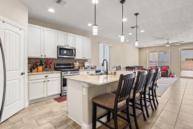 kitchen with a sink, visible vents, white cabinetry, appliances with stainless steel finishes, and backsplash