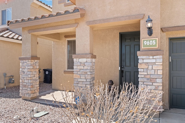 doorway to property featuring a tile roof and stucco siding