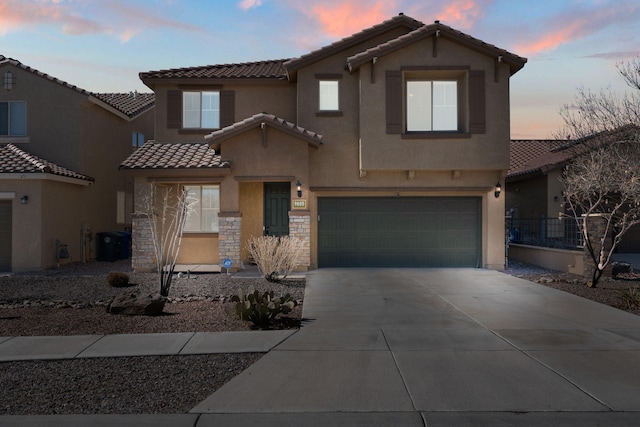 mediterranean / spanish-style house with concrete driveway, stone siding, a tile roof, an attached garage, and stucco siding