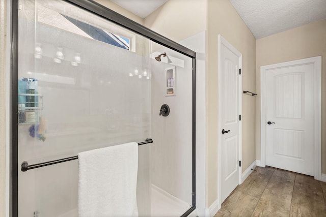 bathroom with a textured ceiling, a shower stall, and baseboards