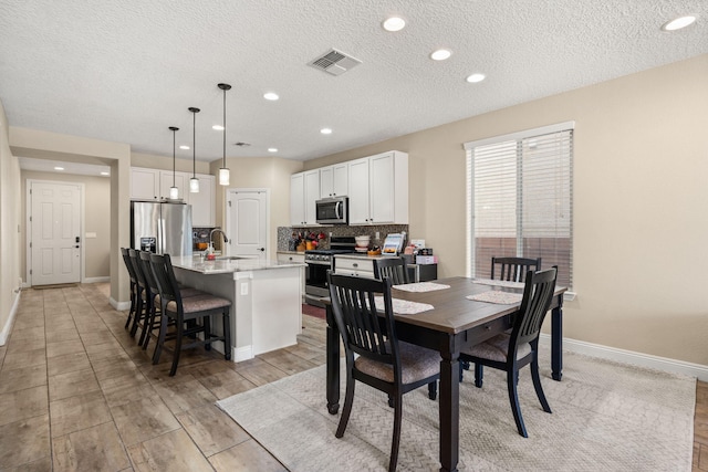 dining area with a textured ceiling, recessed lighting, visible vents, and baseboards