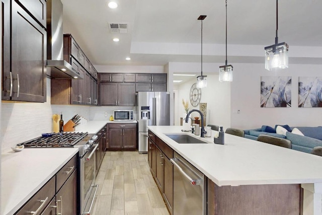 kitchen featuring premium appliances, a sink, light countertops, dark brown cabinets, and pendant lighting