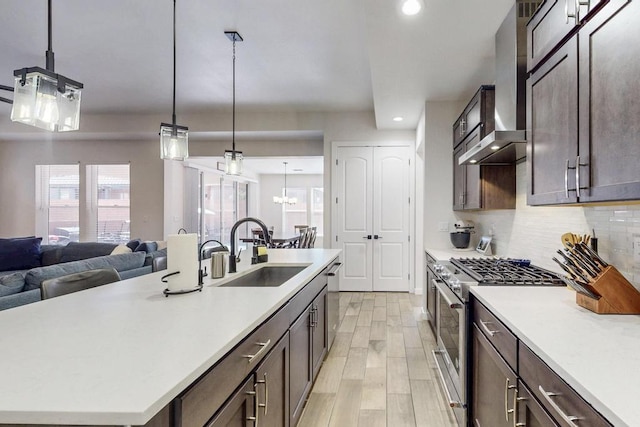 kitchen featuring a kitchen island with sink, a sink, hanging light fixtures, appliances with stainless steel finishes, and light countertops