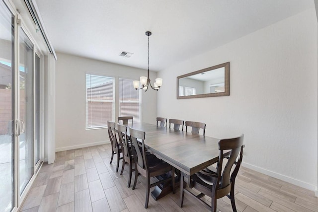 dining area with light wood-style flooring, visible vents, a chandelier, and baseboards