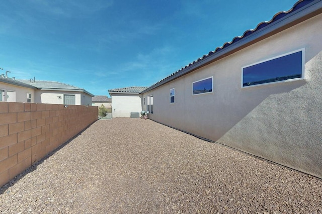 view of property exterior featuring a patio area, fence, a tile roof, and stucco siding