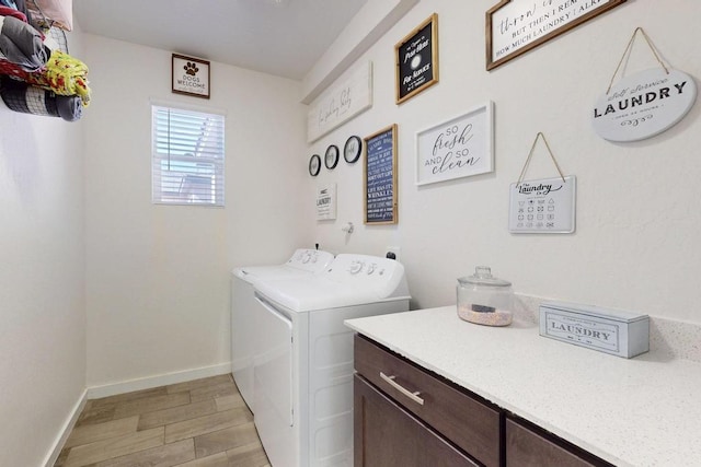 washroom with cabinet space, baseboards, washer and clothes dryer, and light wood-style floors