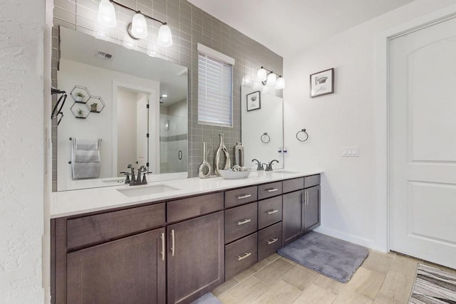 full bathroom featuring double vanity, a stall shower, a sink, and visible vents