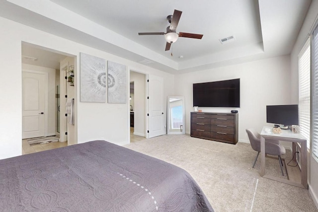 bedroom with visible vents, a tray ceiling, baseboards, and light colored carpet