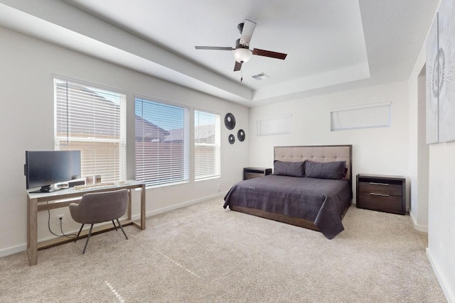 bedroom with light colored carpet, a raised ceiling, visible vents, and baseboards