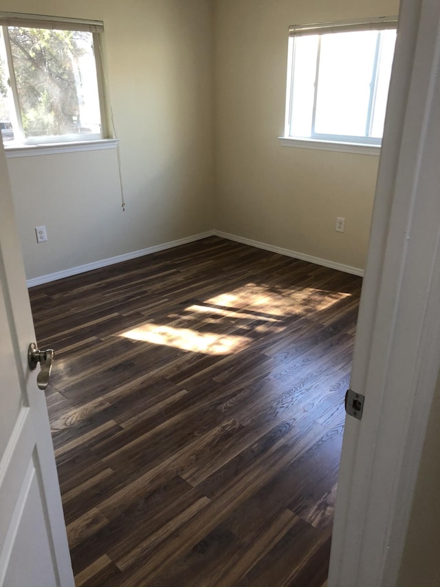 unfurnished room featuring dark wood-type flooring and baseboards