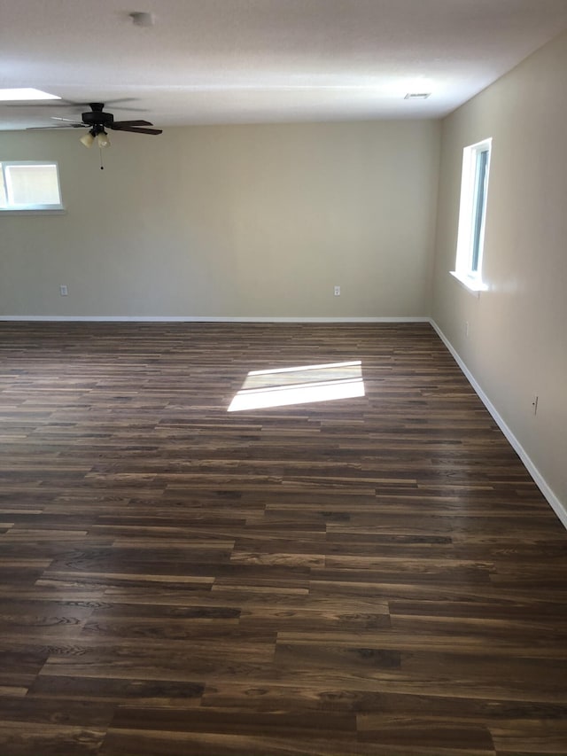 spare room with ceiling fan, baseboards, dark wood finished floors, and a wealth of natural light