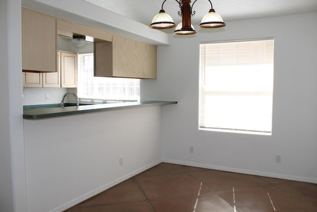 kitchen with baseboards, light brown cabinetry, plenty of natural light, and pendant lighting