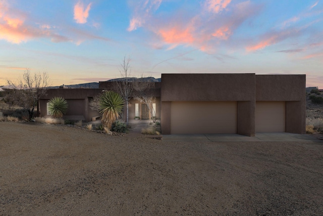 pueblo-style house featuring driveway and stucco siding