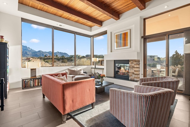 living area featuring visible vents, wood ceiling, a mountain view, beamed ceiling, and a multi sided fireplace