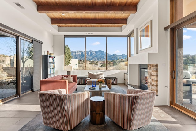 living room featuring beam ceiling, visible vents, wood ceiling, a mountain view, and a multi sided fireplace