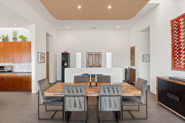 dining room featuring recessed lighting, a raised ceiling, and a toaster