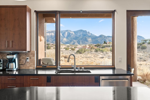 kitchen with a mountain view, a sink, dishwasher, tasteful backsplash, and dark countertops