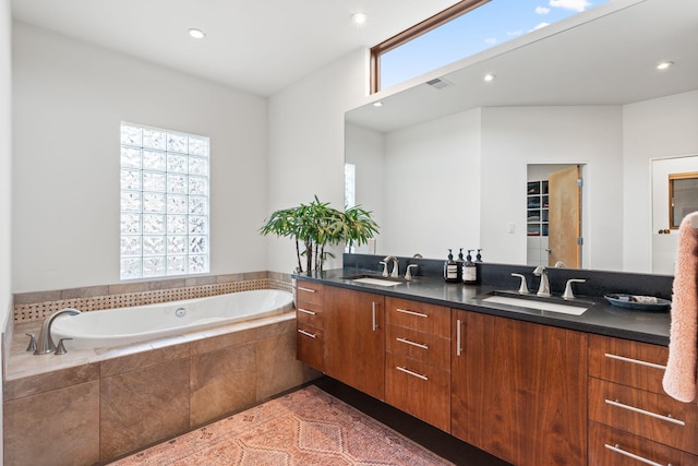 bathroom with recessed lighting, a garden tub, a sink, and double vanity