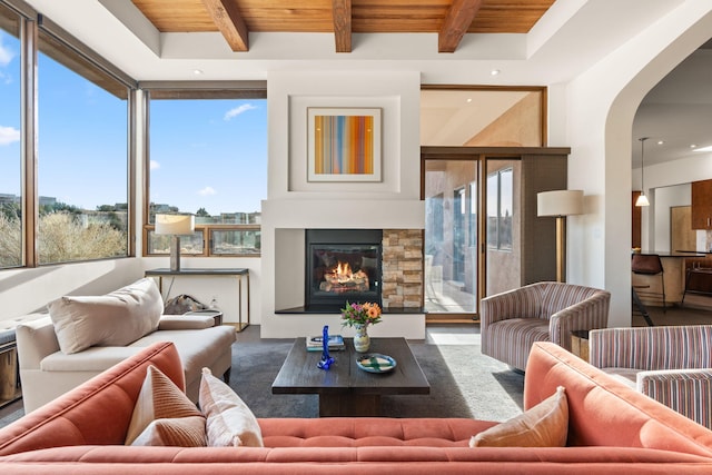 interior space with a glass covered fireplace, wood ceiling, arched walkways, and beam ceiling