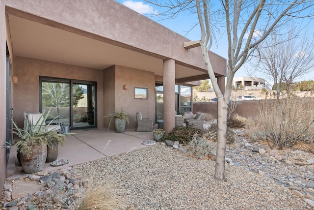 exterior space featuring a patio area, fence, and stucco siding