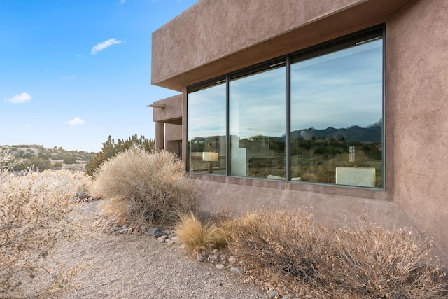 view of side of home with a mountain view and stucco siding