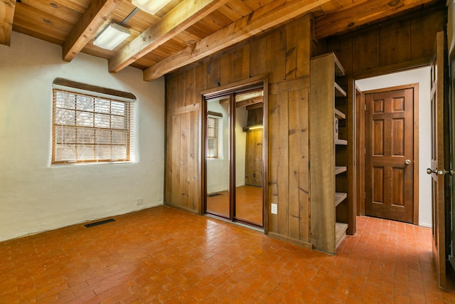 interior space featuring wooden ceiling, visible vents, brick floor, and beam ceiling