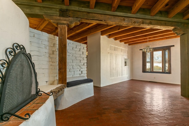 interior space featuring brick floor, visible vents, an inviting chandelier, beamed ceiling, and baseboards