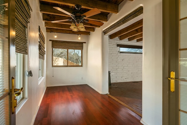 unfurnished room with a ceiling fan, beam ceiling, baseboards, and dark wood-style flooring