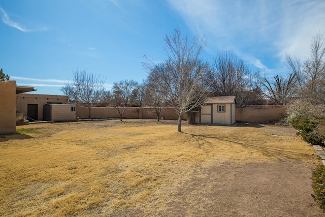 view of yard featuring a shed, a fenced backyard, and an outbuilding