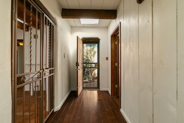 hallway featuring dark wood-style flooring, beamed ceiling, and baseboards