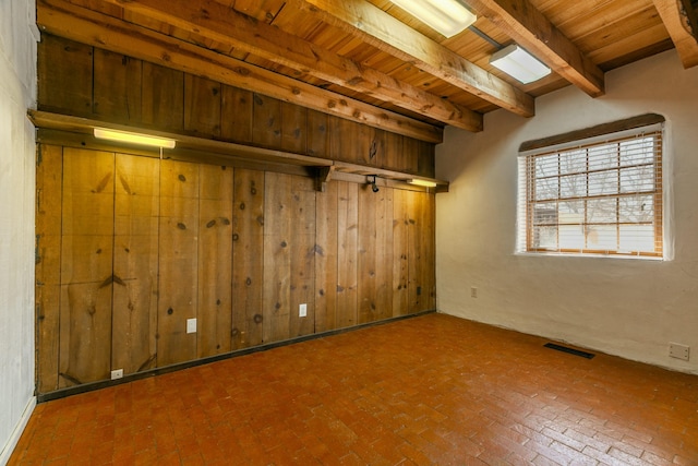 empty room with brick floor, wooden ceiling, and visible vents