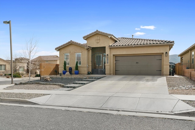 mediterranean / spanish house featuring driveway, an attached garage, a gate, fence, and stucco siding