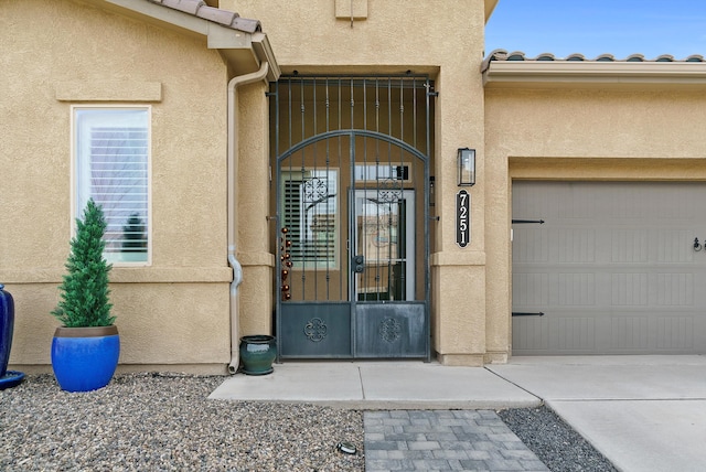 property entrance with an attached garage, a tile roof, and stucco siding