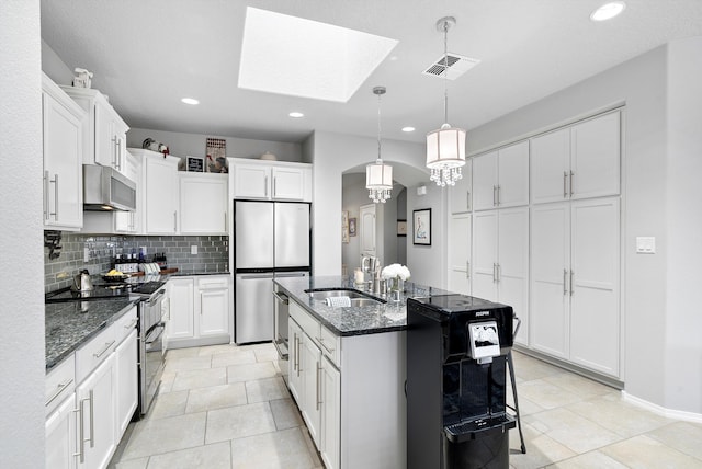 kitchen with a kitchen island with sink, stainless steel appliances, a sink, visible vents, and decorative backsplash