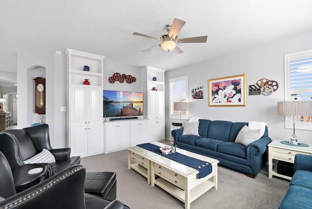 carpeted living area with a textured ceiling, plenty of natural light, and a ceiling fan