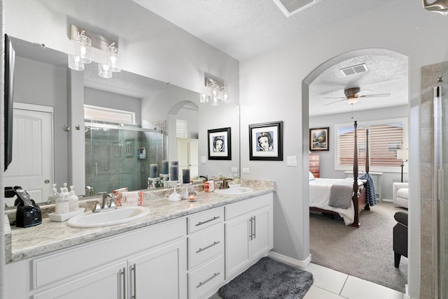 full bathroom featuring a stall shower, a textured ceiling, a ceiling fan, and a sink