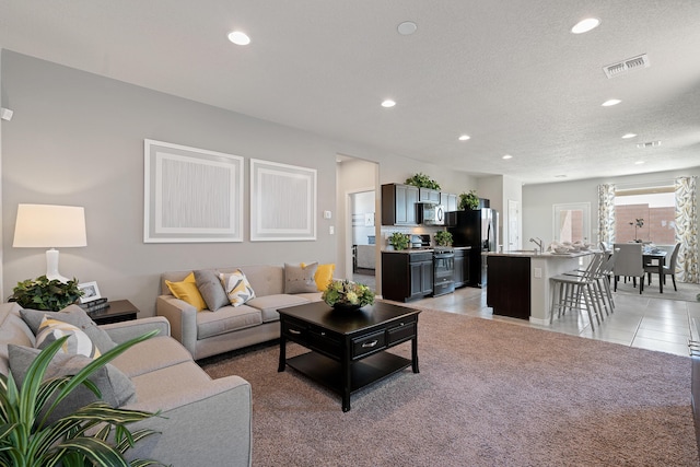 living room featuring recessed lighting, visible vents, a textured ceiling, and light tile patterned floors