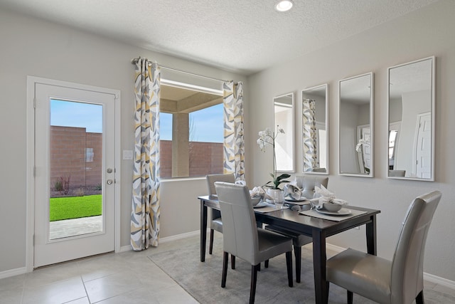 dining area featuring a textured ceiling, light tile patterned floors, plenty of natural light, and baseboards