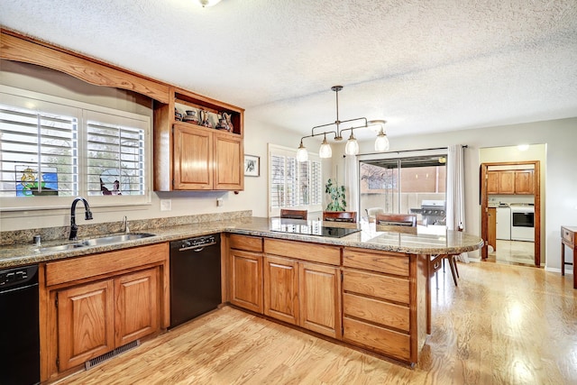 kitchen with a peninsula, separate washer and dryer, a sink, visible vents, and black appliances