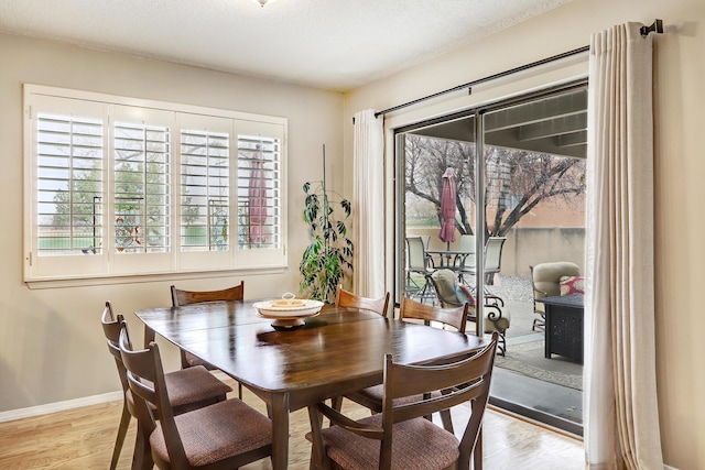 dining space with baseboards and wood finished floors