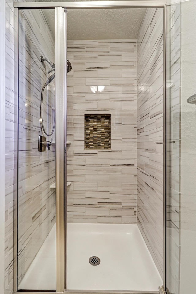 full bathroom with a stall shower and a textured ceiling