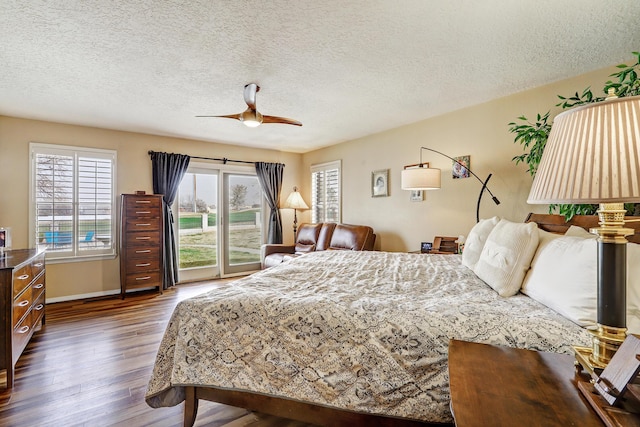 bedroom with access to outside, multiple windows, dark wood finished floors, and a ceiling fan