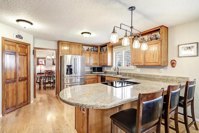 kitchen with stainless steel appliances, light wood-style flooring, a sink, a peninsula, and a kitchen breakfast bar