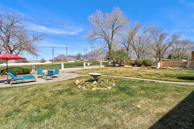 view of yard featuring fence, a mountain view, and a patio